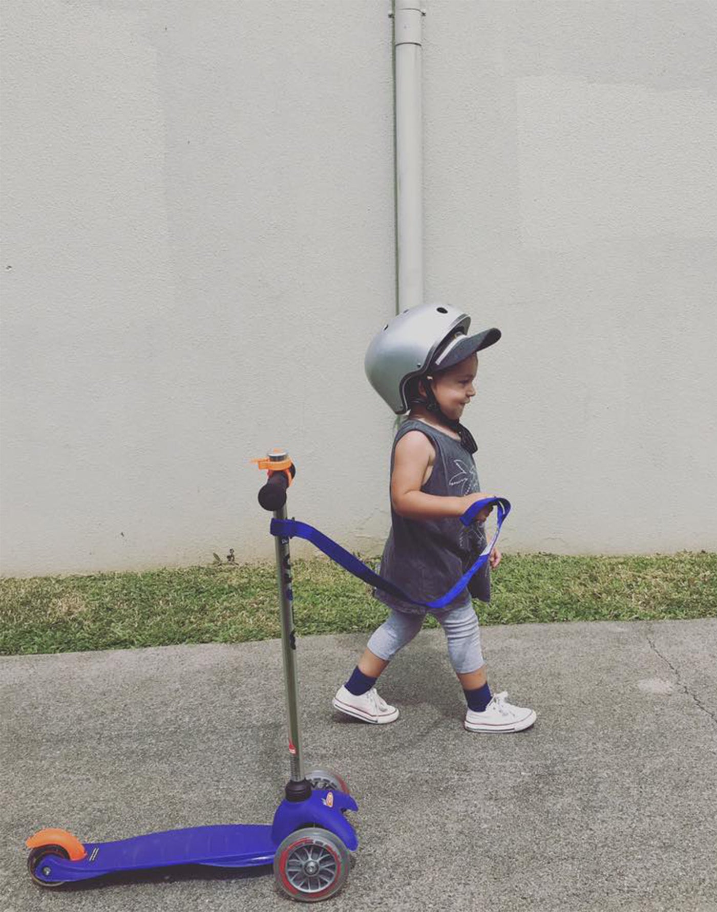 toddler pulling his scooter using a blue scoot n pull strap