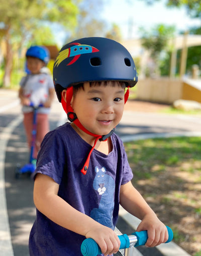 boy wearing rocket and space pattern helmet while scooting