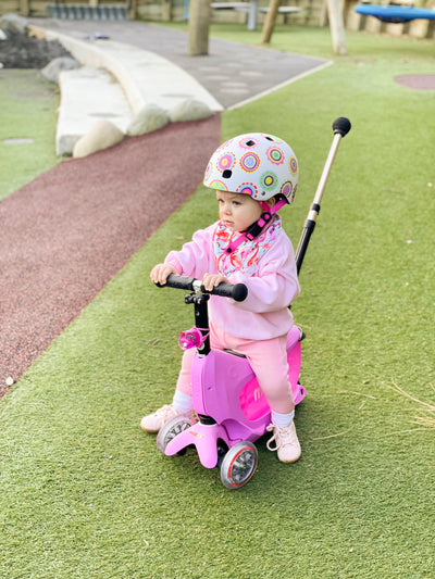 cute toddler on a pink mini2go ride on scooter at the park