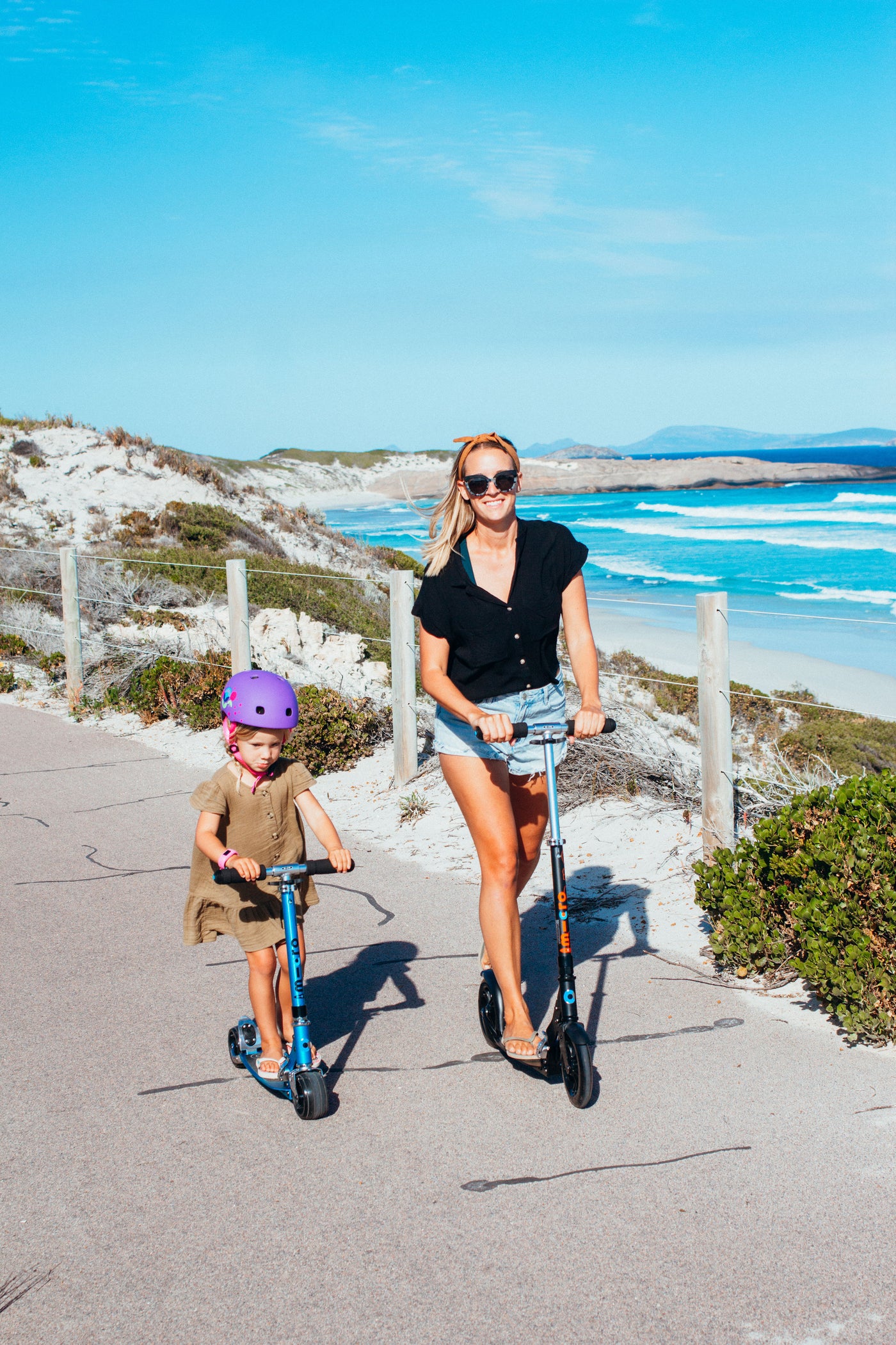 child riding a blue rocket 2 wheel scooter with her mum