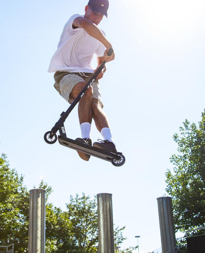 teen doing tricks at the skate park on his stunt ramp scooter
