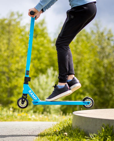 teen doing a jump on cyan blue ramp stunt scooter