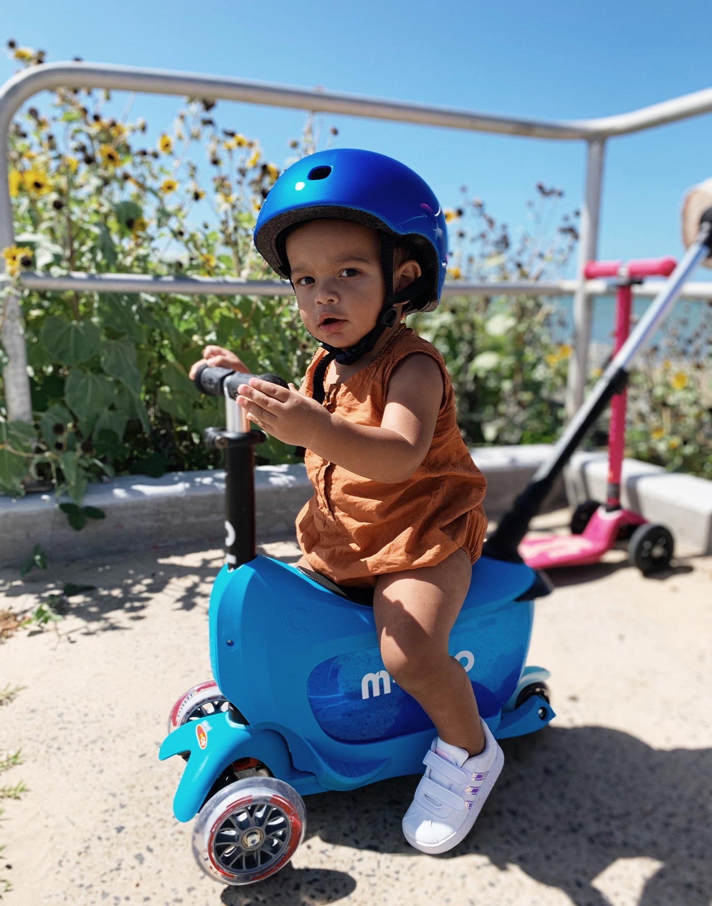 boy on blue mini2go deluxe plus ride on scooter at the beach