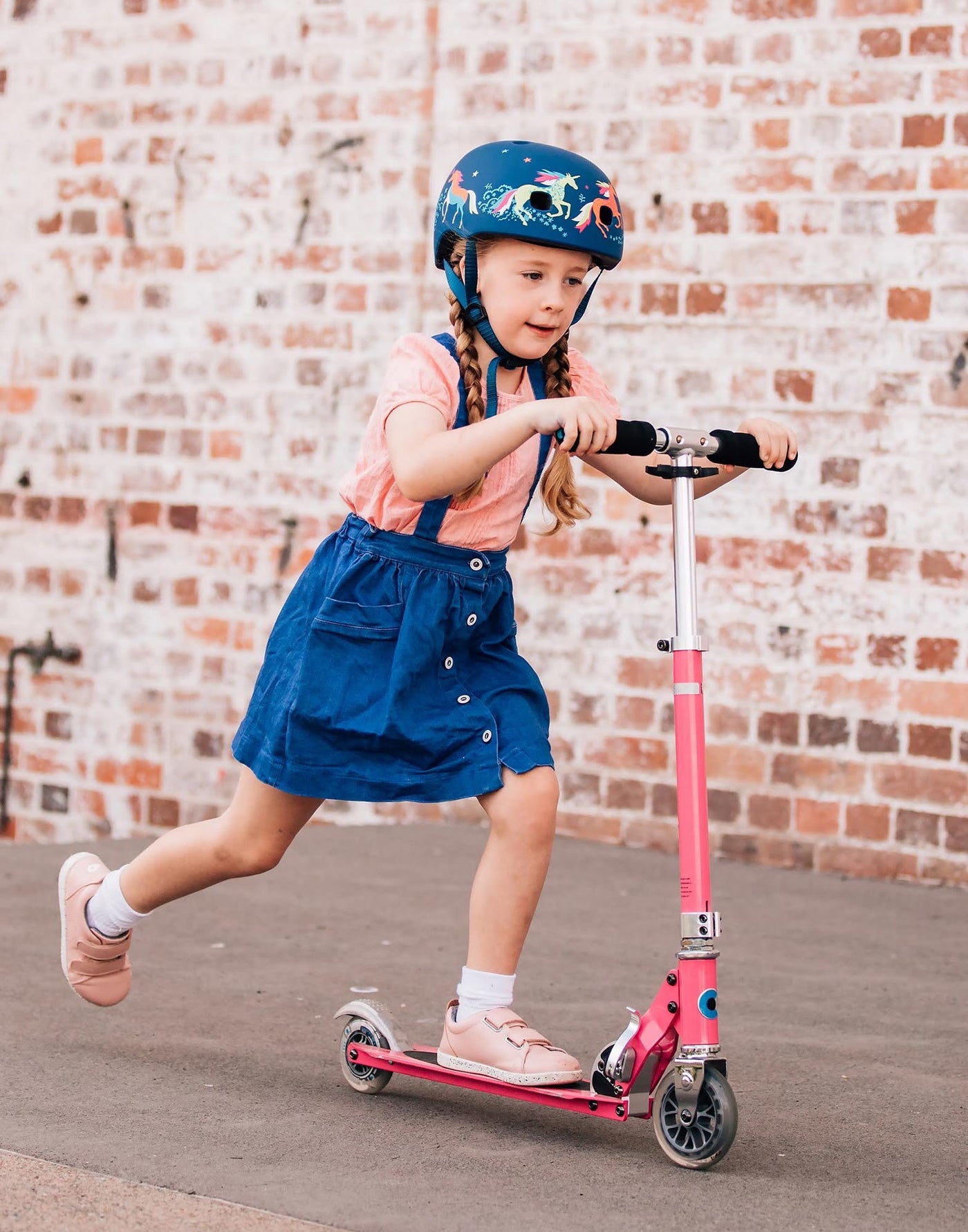 girl on her sprite 2 wheel scooter wearing a unicorn helmet
