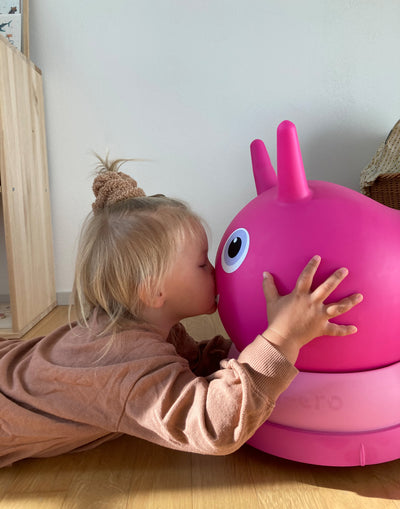 toddler kissing her favourite pink air hopper ride on friend
