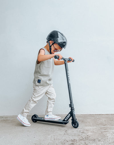 young boy riding a beginner freestyle black ramp scooter